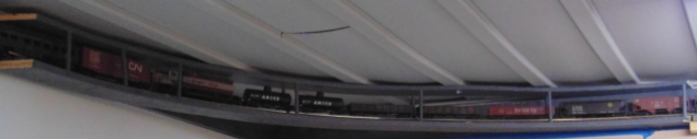a curved bridge of model railroad track with several rail cars