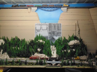 a model railroad layout on a table and a track line at ceiling level, made to look like the inside of a canyon