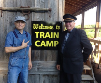 a sign reading welcome to train camp with Mark at its left and John on its right